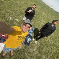 Three friends taking a photo in a field with solar eclipse sunglasses on